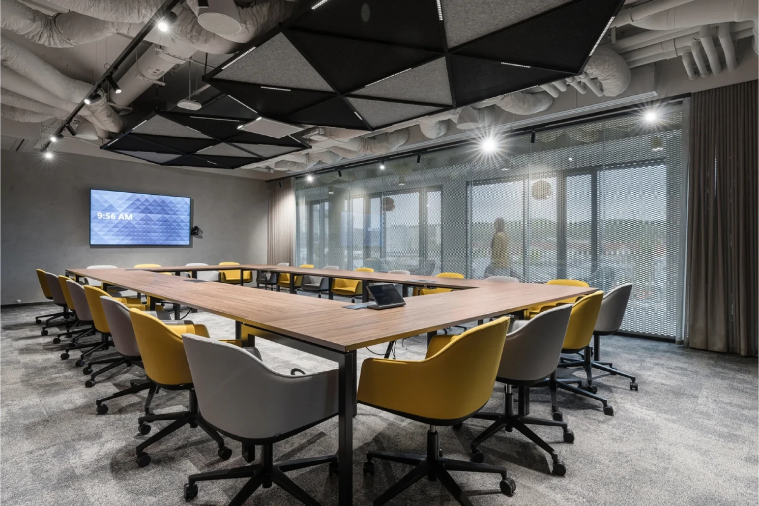 Open-plan office with floor-to-ceiling windows, daylight and suspended oval ring luminaires